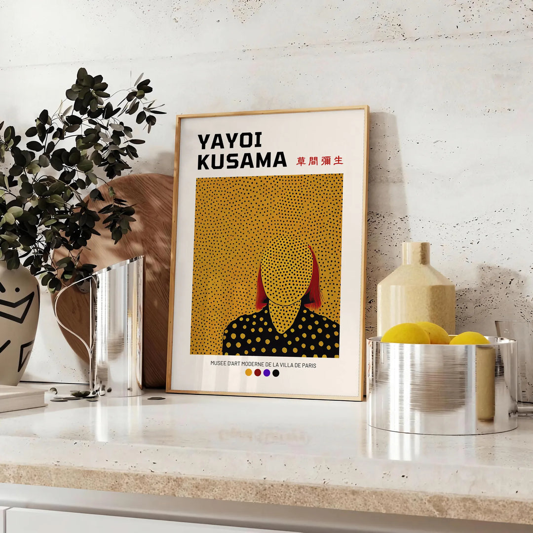 Punti astratti in nero e verde di Yayoi Kusama - su un piano con eucalipto e una ciotola di limoni