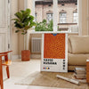 Abstract polka dot patterns in black and orange by Yayoi Kusama - in a Parisian living room with a sofa and a fig plant