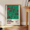 Abstract polka dot patterns in black and blue by Yayoi Kusama - beside a round wooden side table with books