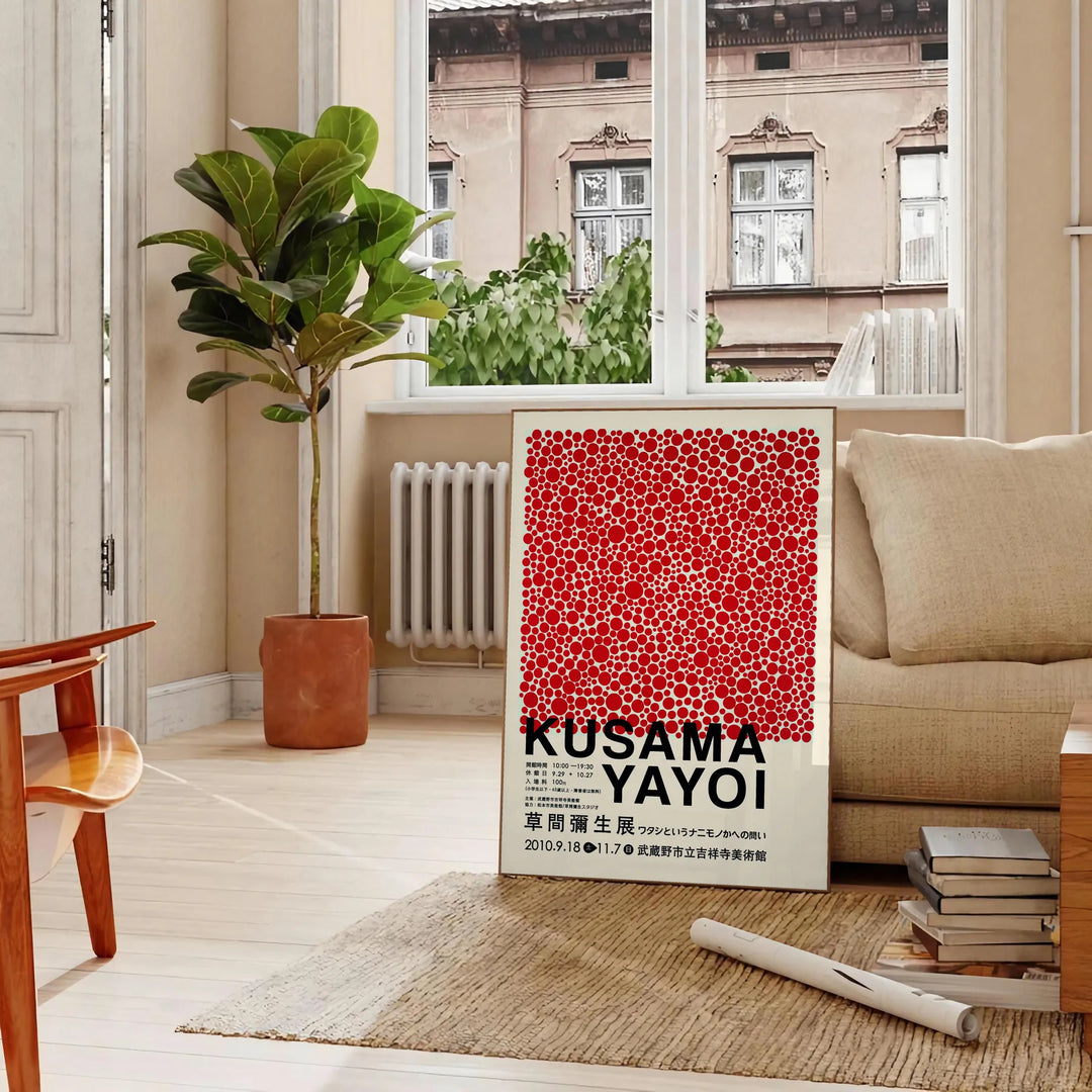 Red dots on a white background with black accents by Yayoi Kusama - in a Parisian living room with a sofa and a fig plant
