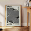 Black and white polka dot patterns with abstract shapes by Yayoi Kusama - beside a round wooden side table with books