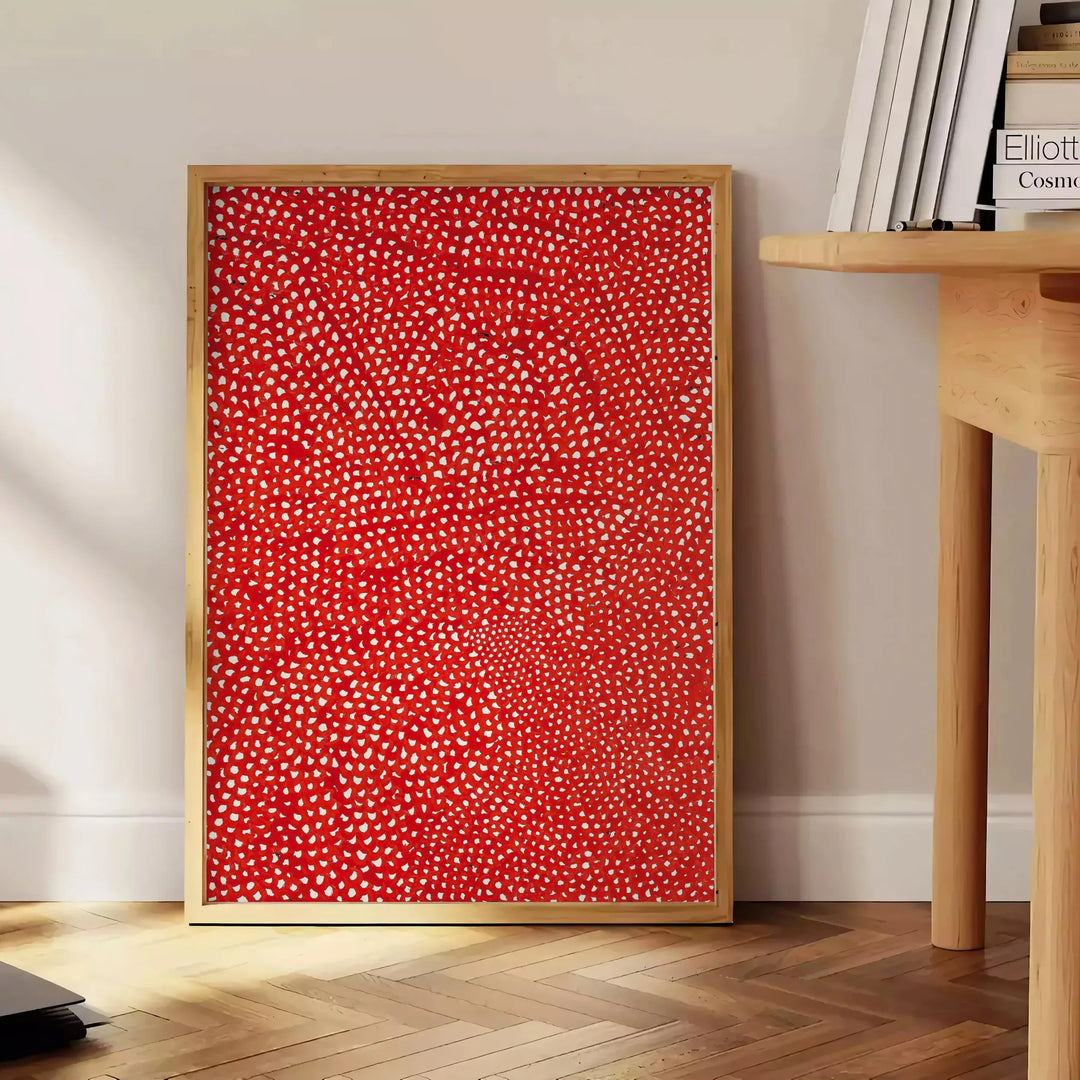 Abstract polka dot patterns in orange and brown by Yayoi Kusama - beside a round wooden side table with books