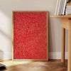 Abstract polka dot patterns in orange and brown by Yayoi Kusama - beside a round wooden side table with books