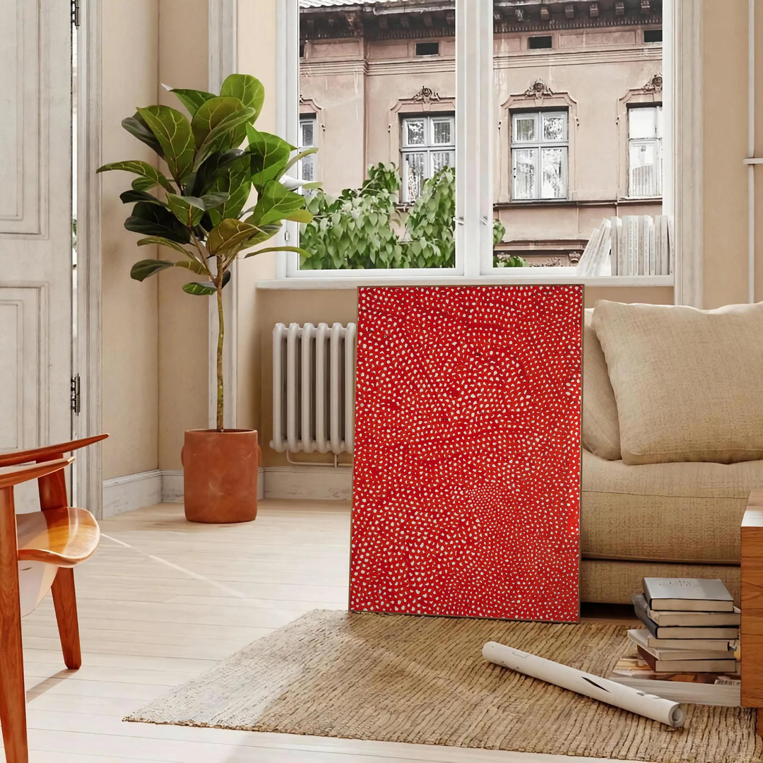 Abstract polka dot patterns in orange and brown by Yayoi Kusama - in a Parisian living room with a sofa and a fig plant