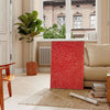 Abstract polka dot patterns in orange and brown by Yayoi Kusama - in a Parisian living room with a sofa and a fig plant
