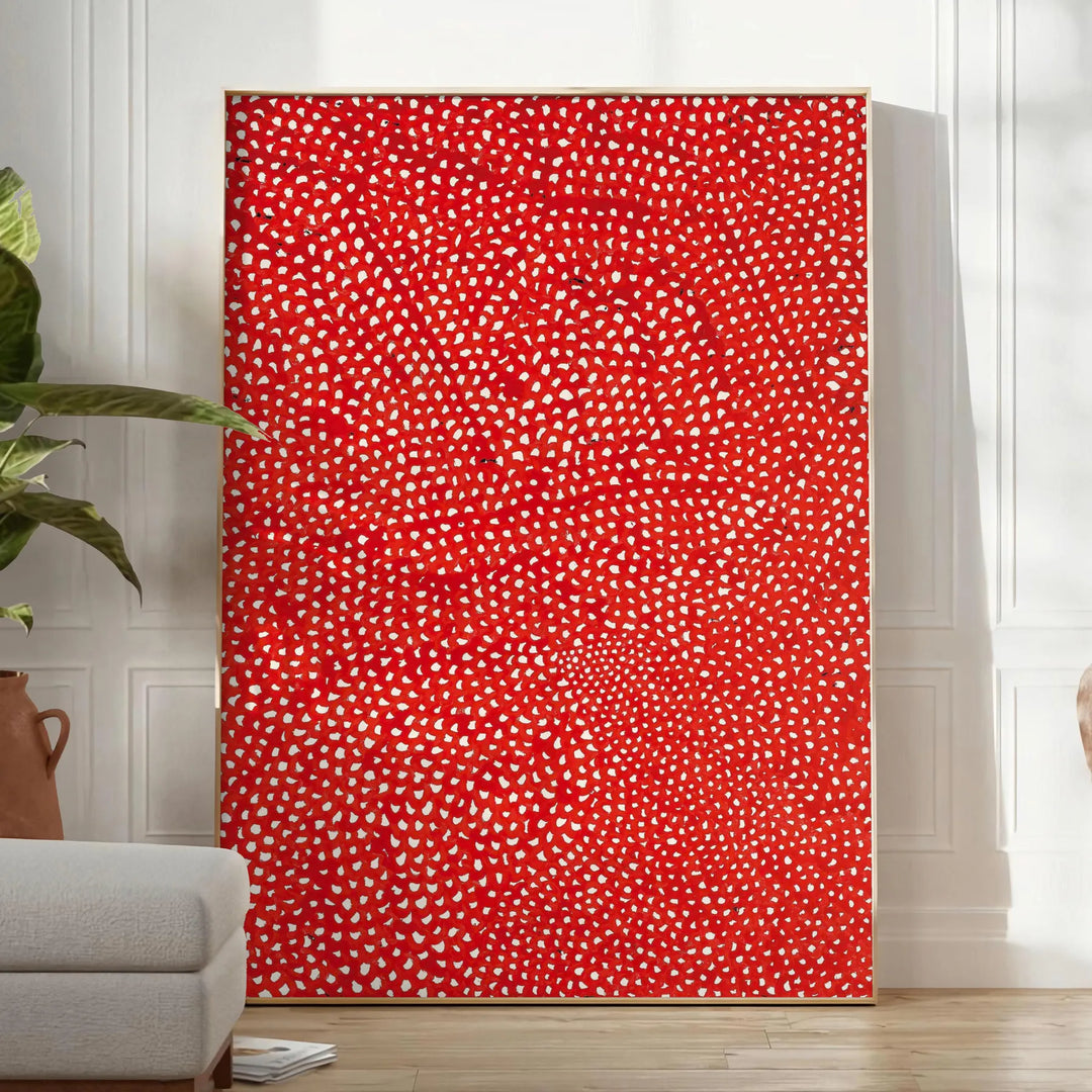 Abstract polka dot patterns in orange and brown by Yayoi Kusama - in a bright minimalist room with a plant and an armchair