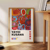 Colorful polka dots in green and orange by Yayoi Kusama - beside a round wooden side table with books