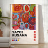 Colorful polka dots in green and orange by Yayoi Kusama - in a bright minimalist room with a plant and an armchair