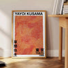 Motivi astratti a pois in nero e marrone di Yayoi Kusama - accanto a un tavolino rotondo in legno con libri