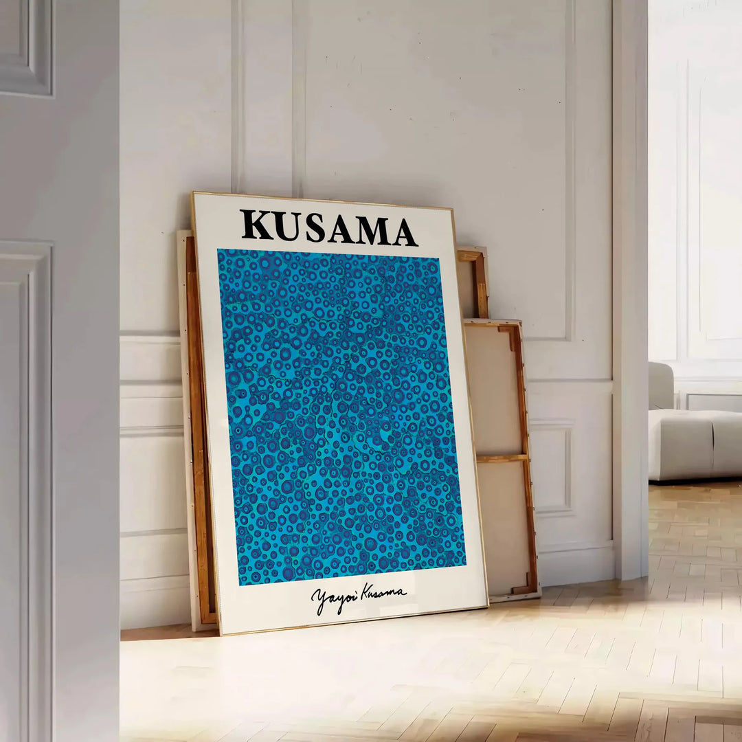 Abstract polka dot patterns in blue and black by Yayoi Kusama - leaning on a herringbone floor against a white panelled wall