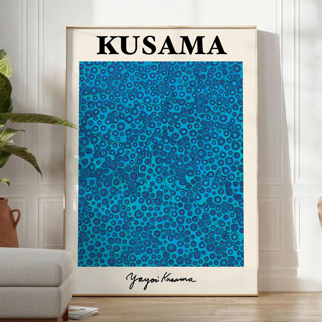 Abstract polka dot patterns in blue and black by Yayoi Kusama - in a bright minimalist room with a plant and an armchair