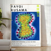 Colorful polka dots in various sizes on a deep blue background by Yayoi Kusama - in a bright minimalist room with a plant and an armchair