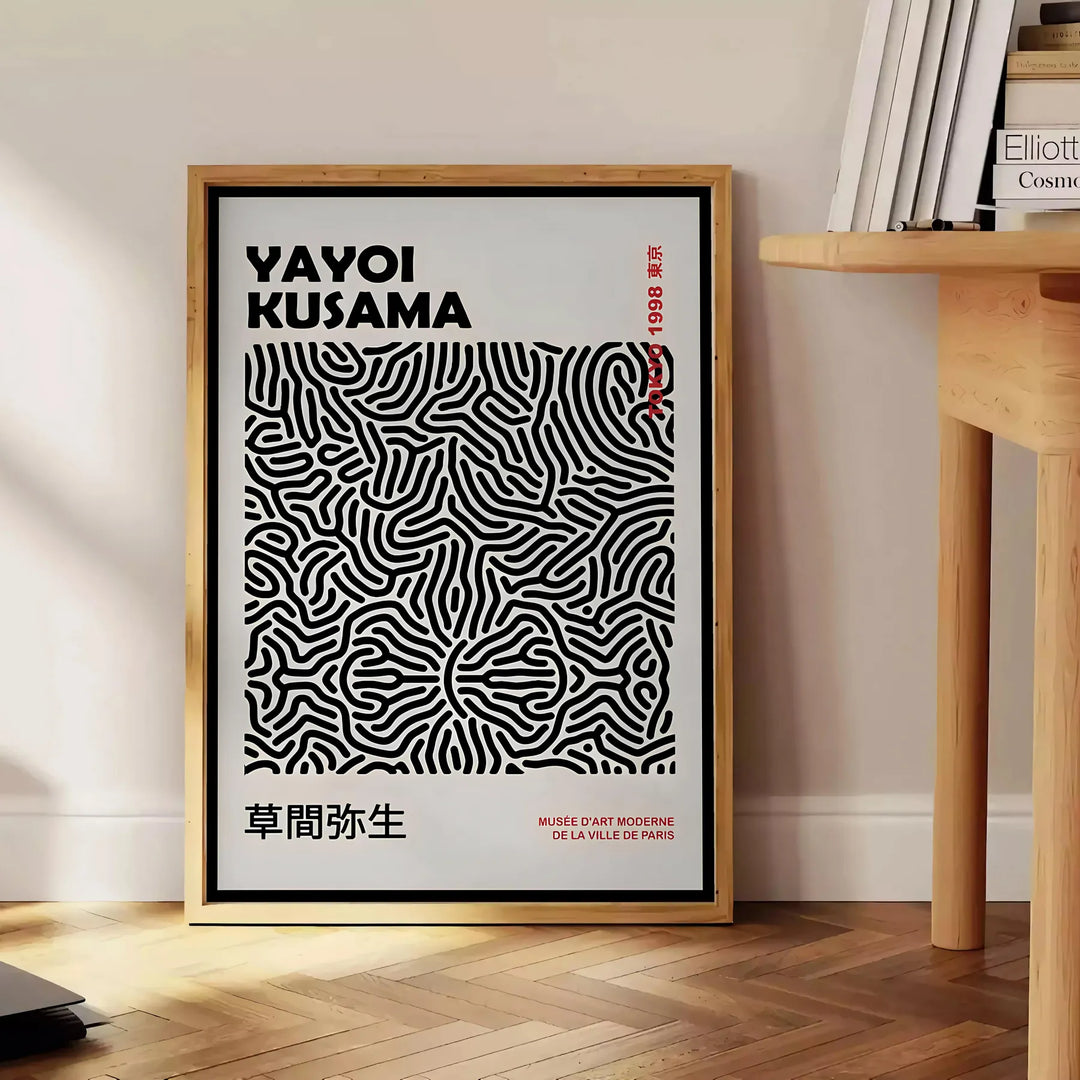 Abstract polka dot patterns in black and gray by Yayoi Kusama - beside a round wooden side table with books