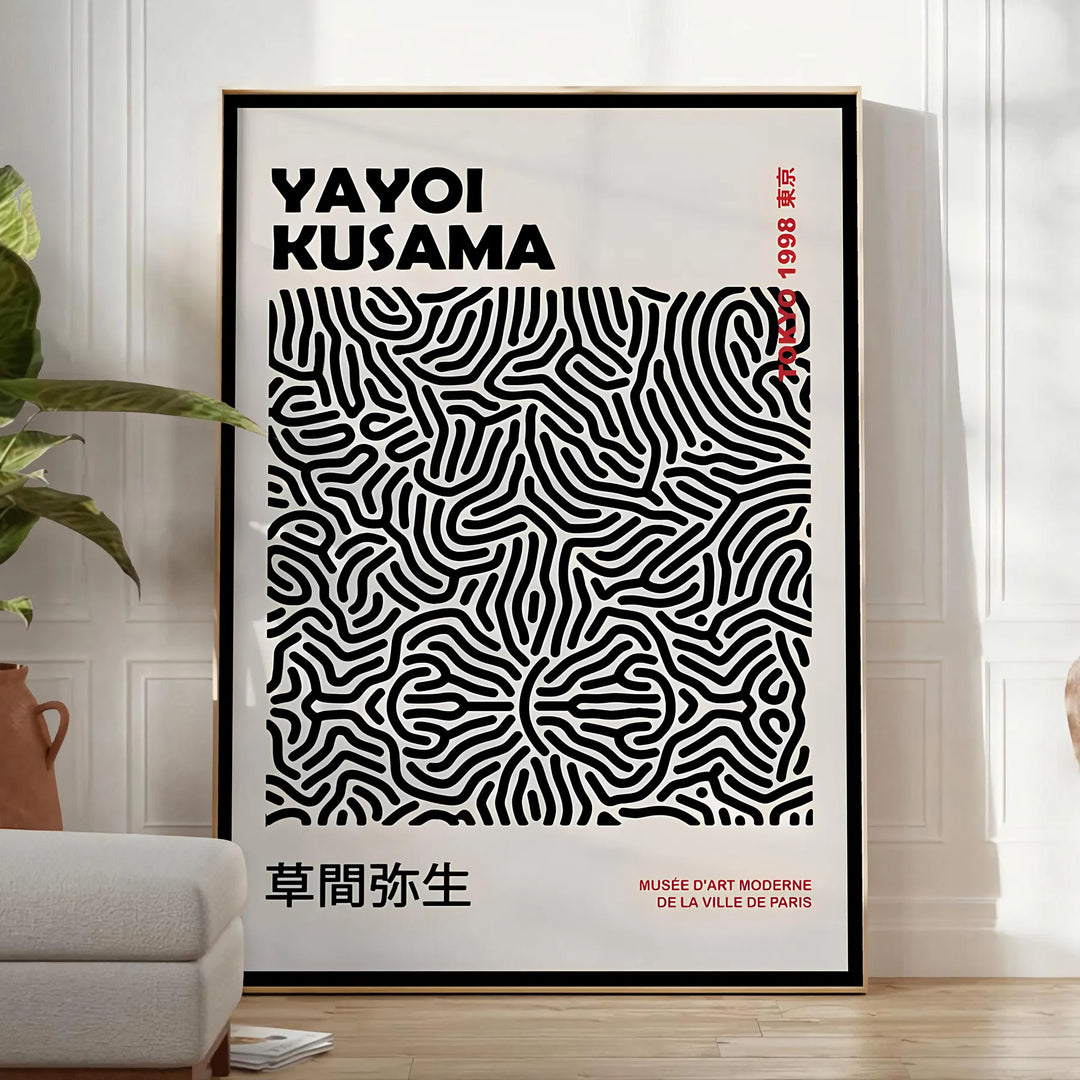 Abstract polka dot patterns in black and gray by Yayoi Kusama - in a bright minimalist room with a plant and an armchair
