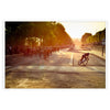 Dynamic cycling scene with cyclists racing through a green landscape under an orange sky - in a white frame