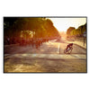 Dynamic cycling scene with cyclists racing through a green landscape under an orange sky - in a black frame